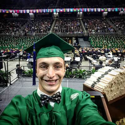 MSU advertising alumni Derek Black taking a selfie at commencement ceremony.