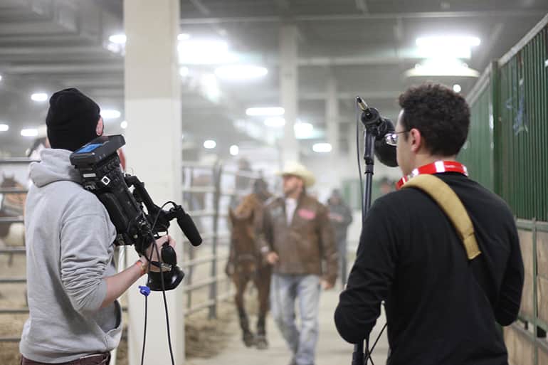 Two male students from Media and Information class 491: Live Event Production for Broadcast, shooting the Spartan Stampede, a professional rodeo. 
