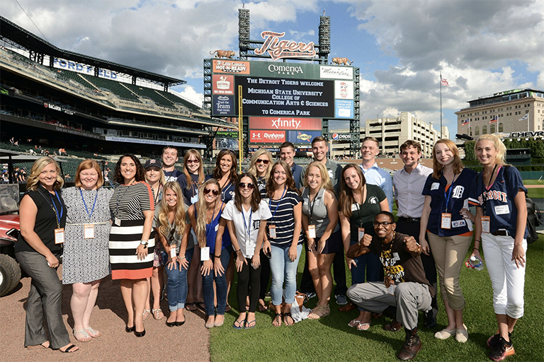 A large group of advertising students in the field of the Detroit Tiger Baseball stadium.