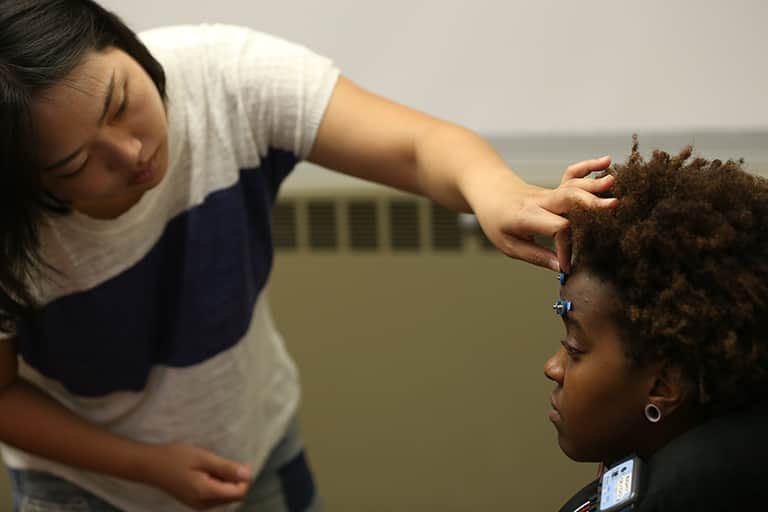 MAP lab graduate student placing sensors on the forehead of student for advertising study.