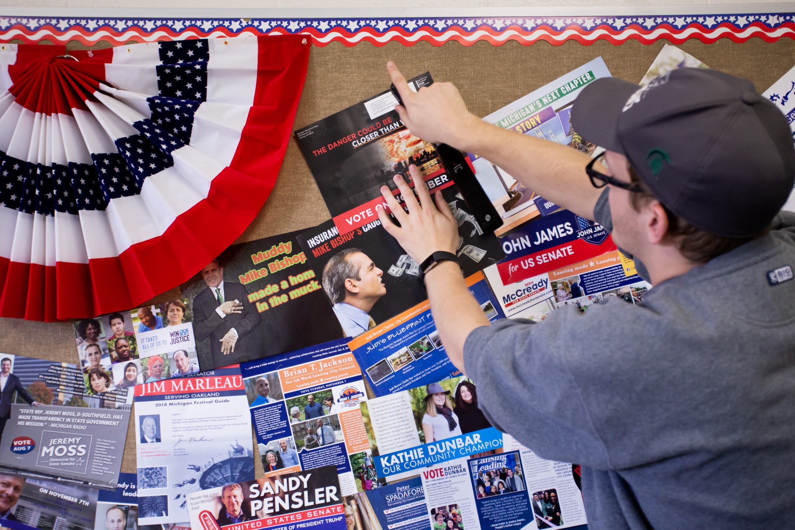 student stapling campaign poster to a cork board