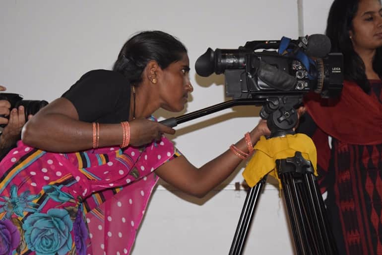 indian women behind movie camera shooting a scene.