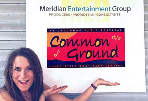 Margaux Koepele smiling and pointing at the Meridian Entertainment Group sign.