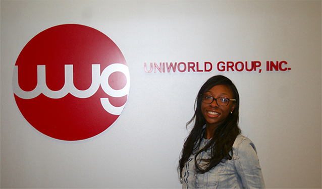 Maya Parnell standing next to Uniworld Group sign.