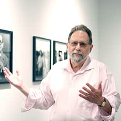 Portrait of Howard Bossen in a gallery with one of the exhibitions he has curated