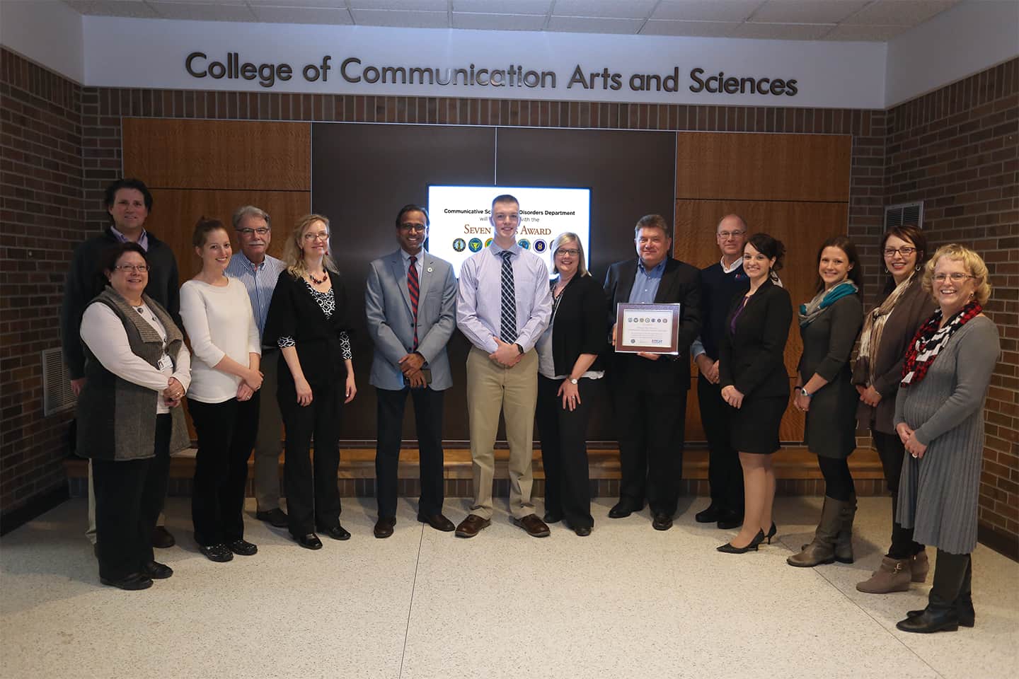 Blake Donovan with Communicative Sciences and Disorders department faculty and staff standing in lobby of the College of Communication Arts and Sciences building.