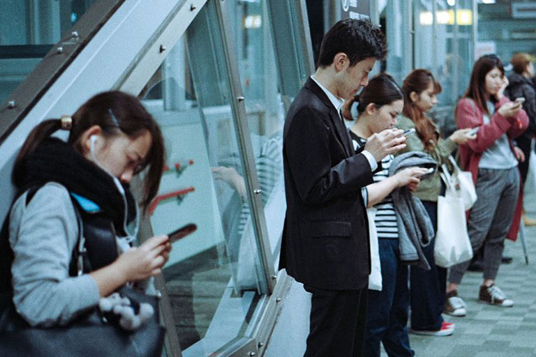 A group of people standing and texting on their phones