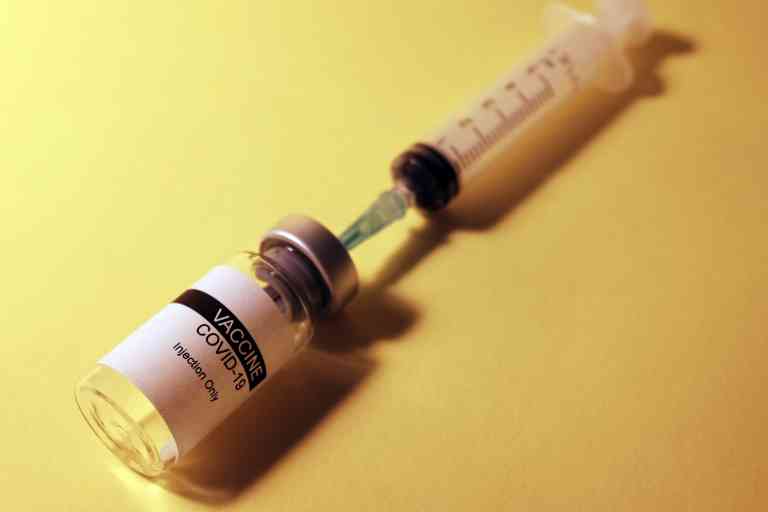 Image of a bottle of COVID vaccine with an injection needle