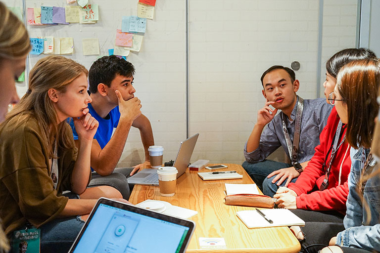 Students sitting at a table discussing a project