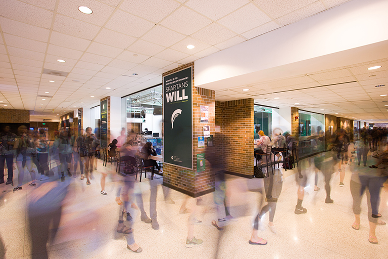 Timelapse photo taken of ComArtSci building hallway with people walking