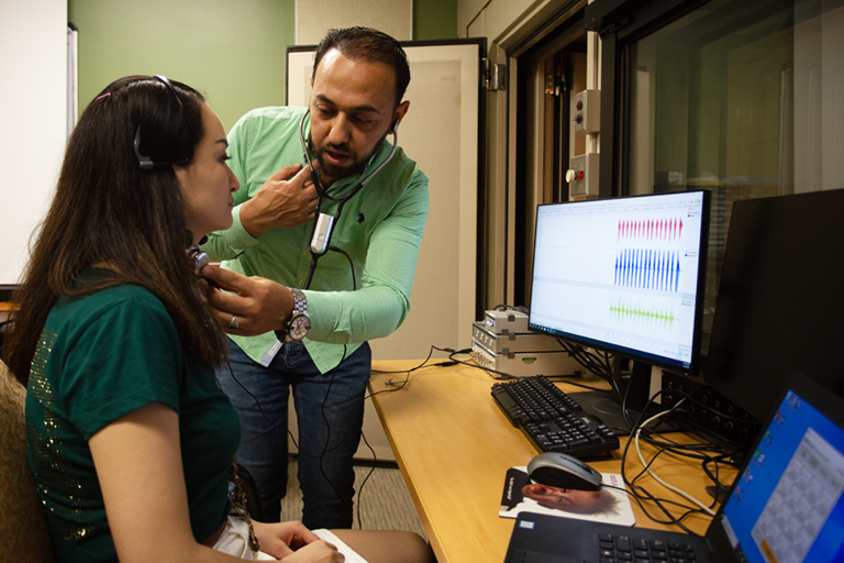 Two Ph.D. students in the Analysis Voice and Hearing Lab testing out the equipment