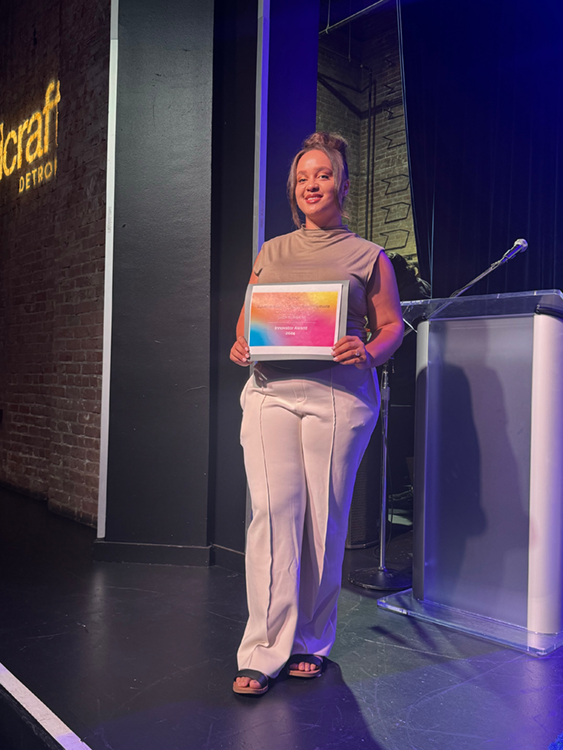 Jada Flowers standing on stage with her award