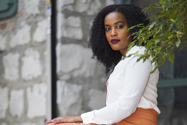 Photo Shaniqua Davis sitting down in front of a light brick wall