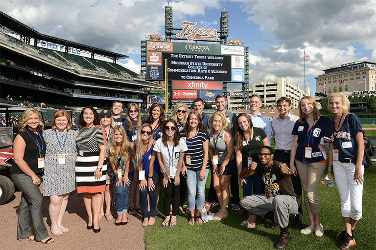 A large group of advertising and public relations students in the field of the Detroit Tiger Baseball stadium.