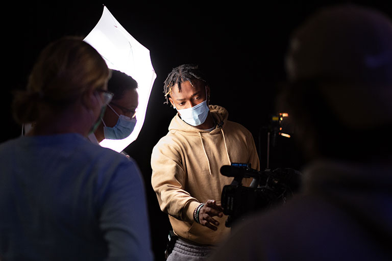 Photo of students working with a professor on a video camera