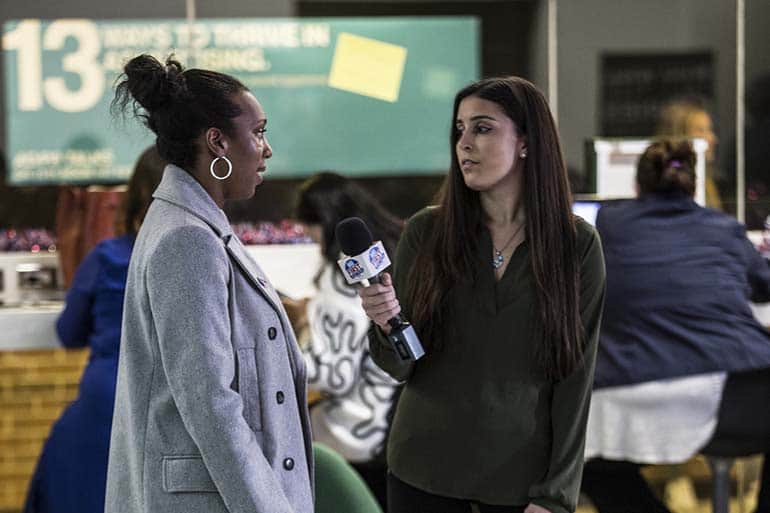 Journalism student with microphone interviewing another student.