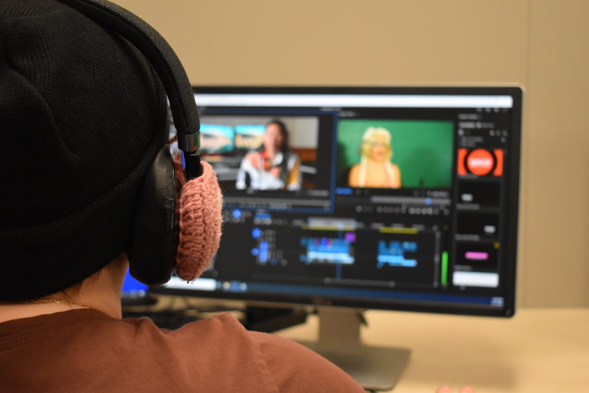 student with headphones on, working on a computer editing a documentary film