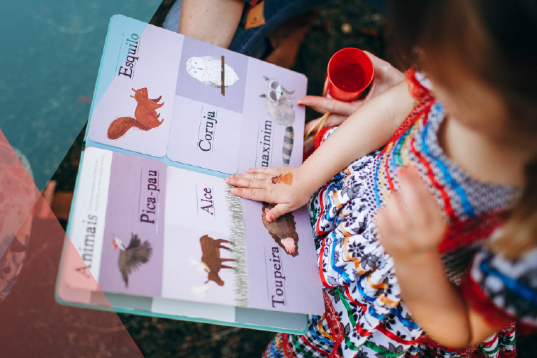 Photo of a child reading and pointing at a book