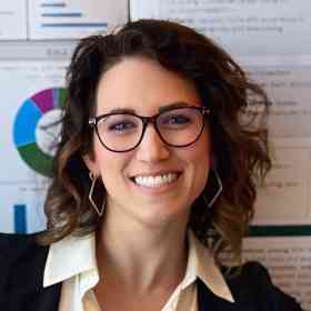 Photo of Kathryn Genoa-Obradovich in front of white poster with graphs