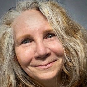 Photo headshot of person with medium-length light hair and green eyes.
