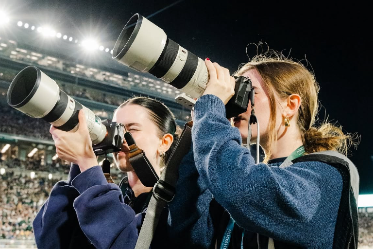Visual storytelling students taking photos at football game