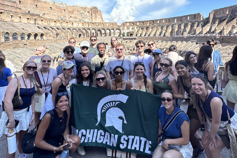 Study abroad students standing with MSU flag