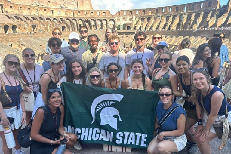 Students with MSU flag inside colosseum