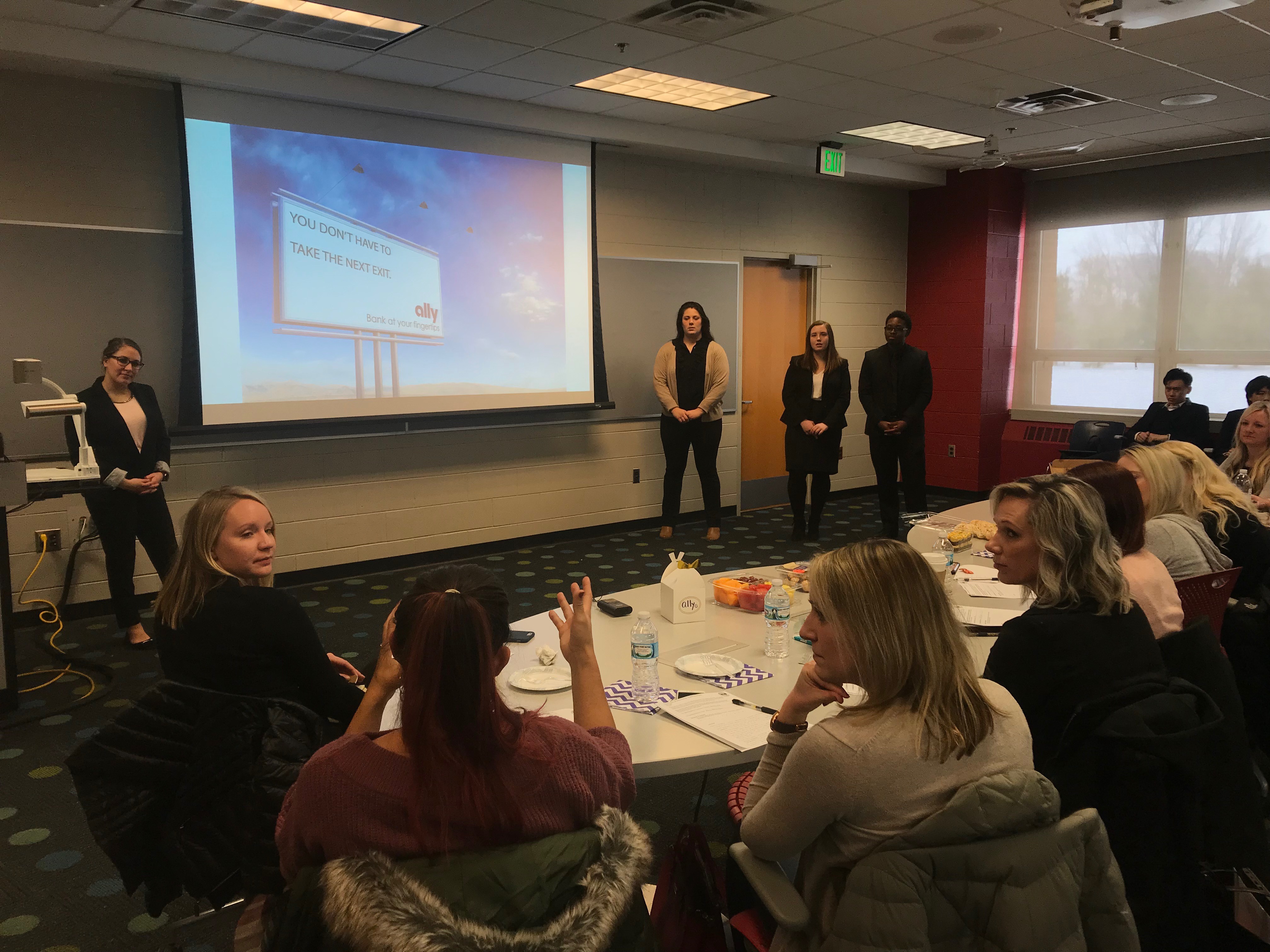 Students give a presentation to a table full of clients