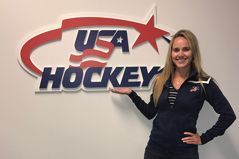 Alexis Downie standing next to a USA Hockey sign