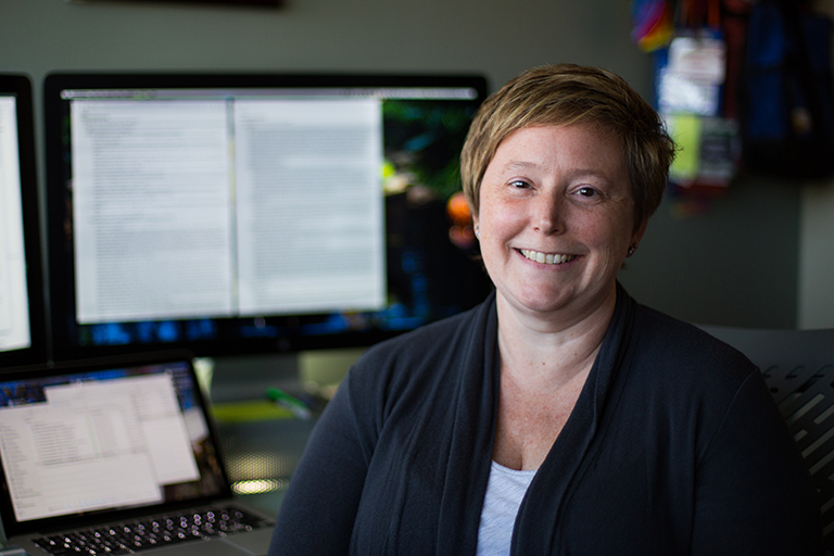 Associate professor Emilee Rader smiling in front of her desktop computer.