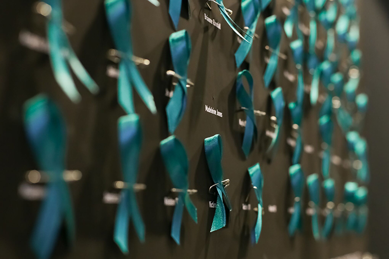 Poster of teal ribbons that hangs in the ComArtSci hallway