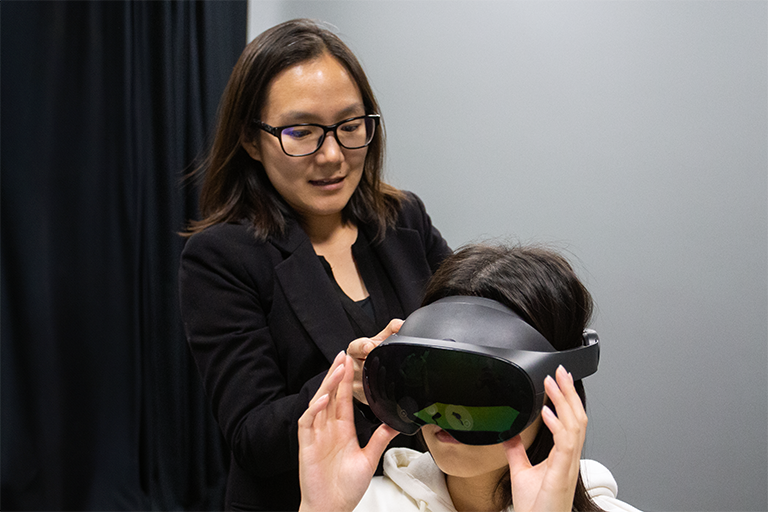 CARISMA Lab researcher assists with putting on the VR headset.