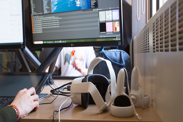 view of a game development program in the background and a VR headset in the foreground