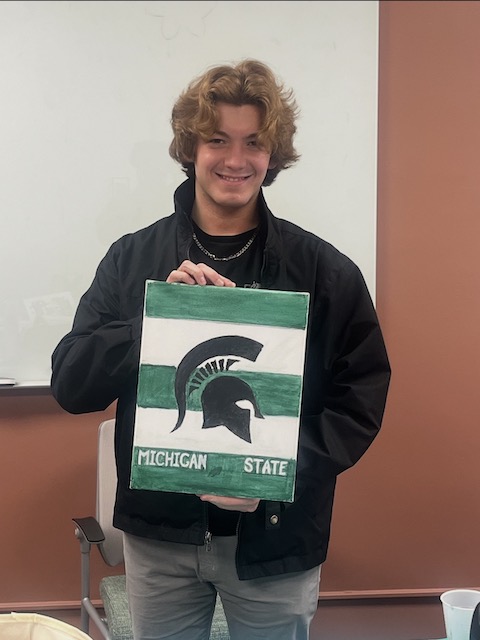 Patrick Fitzsimons holding a painting of the Spartan mascot.